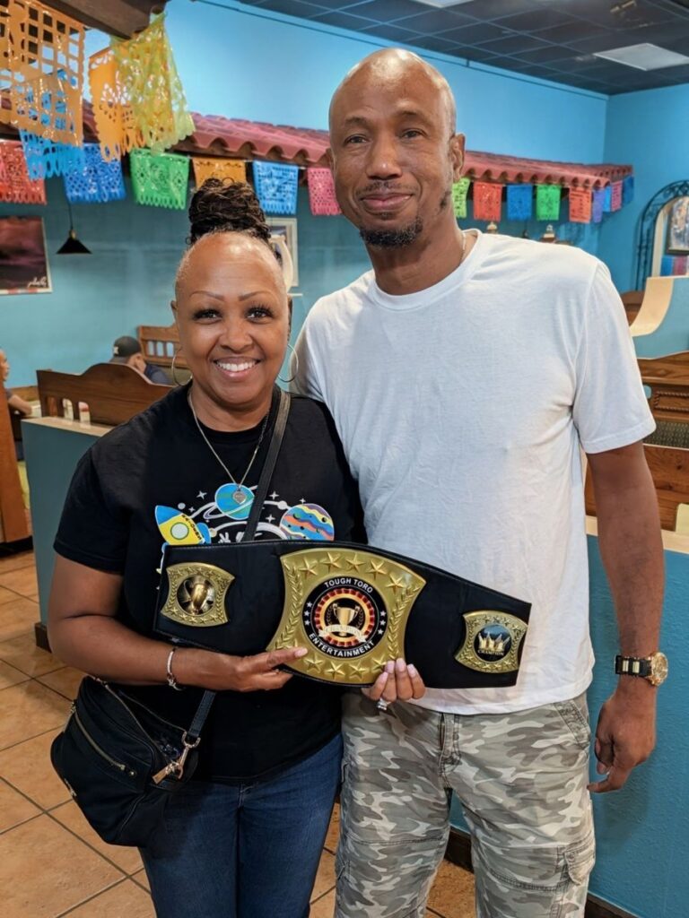 Two trivia winners posing with the championship belt