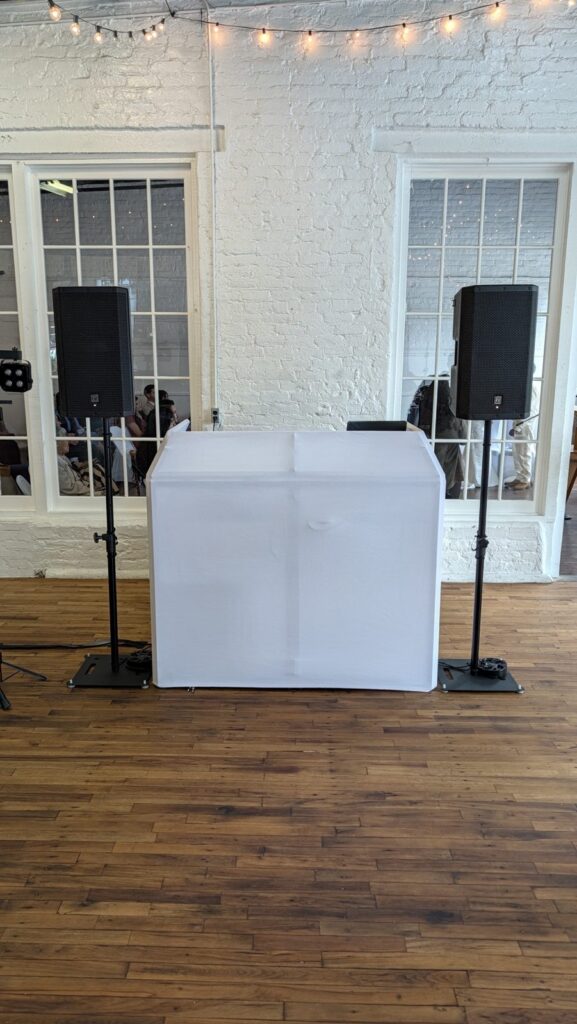 White DJ booth and speakers set up in a wedding venue